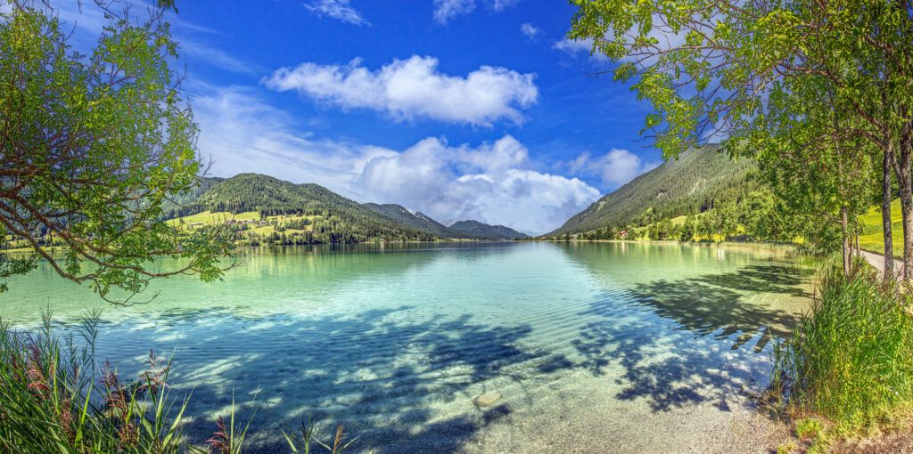 Türkisblauer Weissensee in Kärnten mit grünen Bergen und bewaldetem Ufer